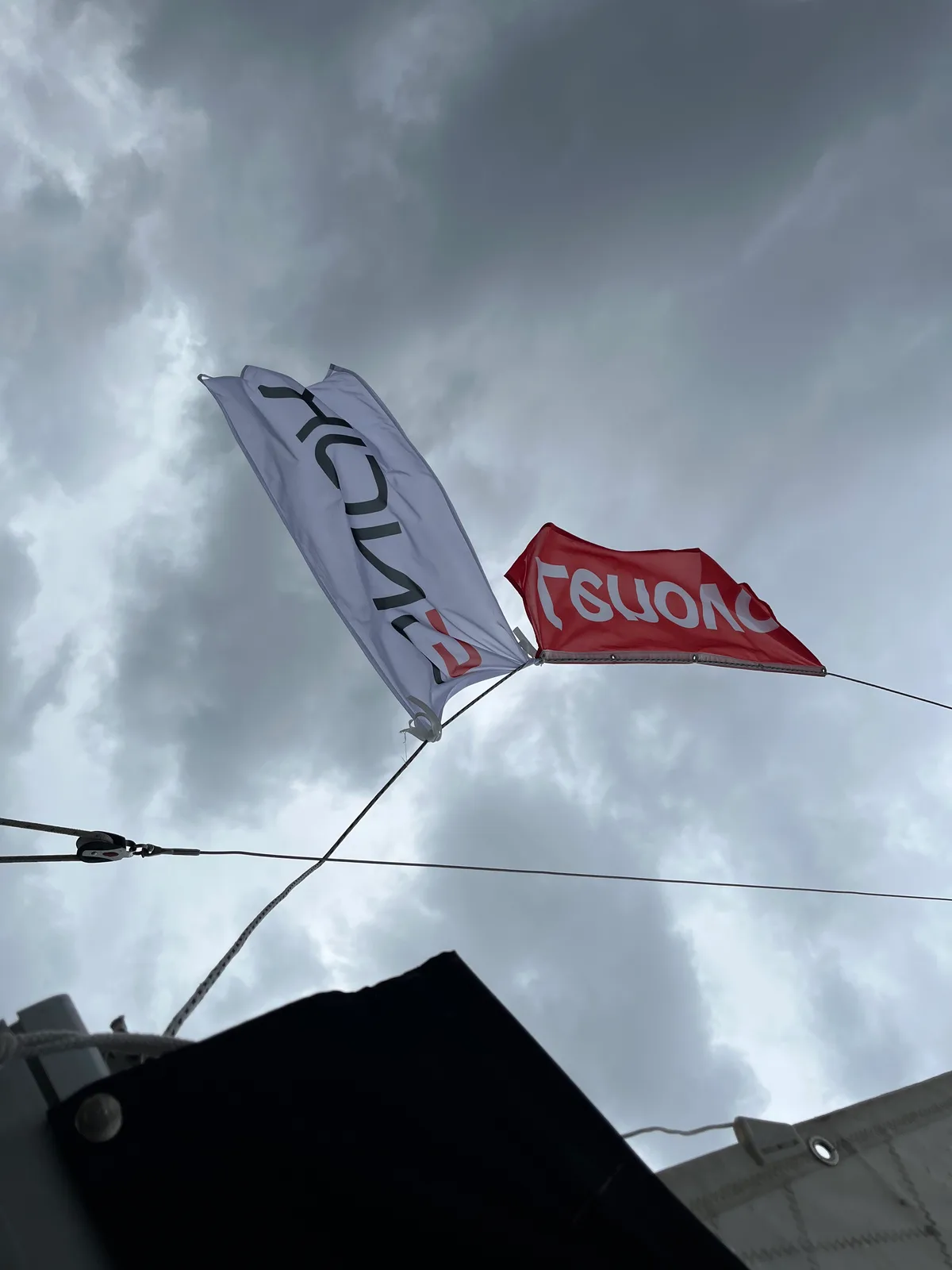 Te same flagi Lenovo i SNOK pod ciężkimi chmurami nad jeziorem Bełdany